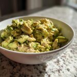 A bowl of creamy Avocado Tuna Salad, seasoned with black pepper, perfect for a quick lunch.
