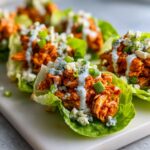 Close-up of Buffalo Chicken Lettuce Wraps topped with blue cheese crumbles and green onions.