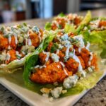 Close-up of spicy Buffalo Chicken Lettuce Wraps topped with blue cheese crumbles and a drizzle of ranch.