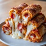A stack of golden-brown Cheesy Pizza Rolls filled with gooey mozzarella cheese and pepperoni slices.