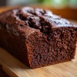Close-up of a moist chocolate wacky cake loaf on a wooden board, showcasing its texture.