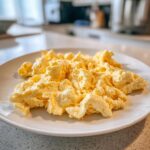 Close-up of perfectly creamy scrambled Eggs served on a white plate, ready to eat.