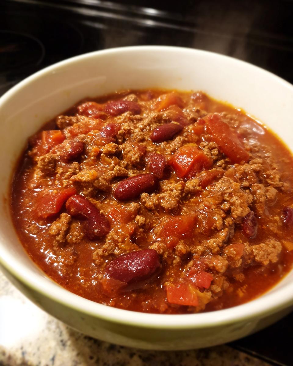 A bowl of hearty chili recipe easy, featuring ground beef, kidney beans, and diced tomatoes in a rich, red broth.