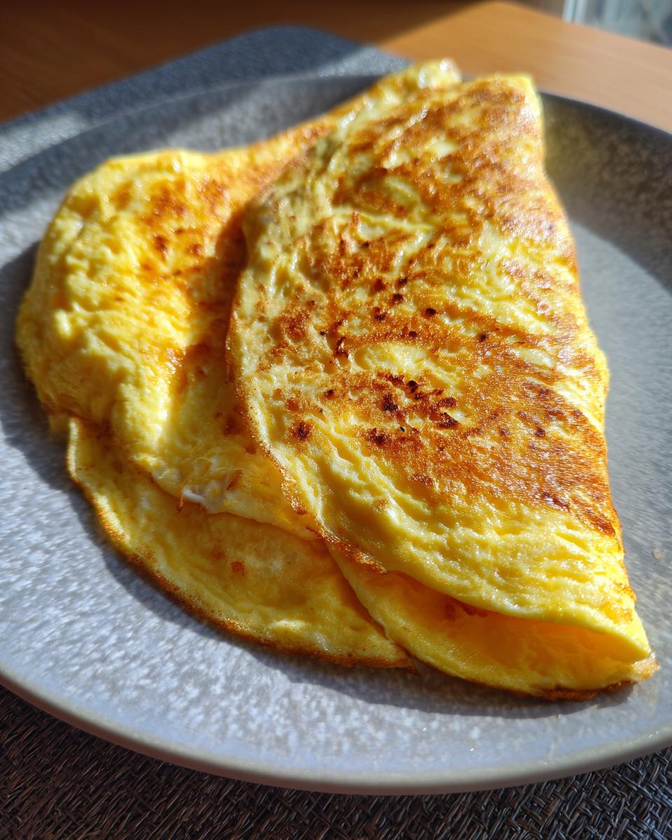 A golden-brown omelet folded on a gray plate, ready to eat. Quick and easy omelet recipe.