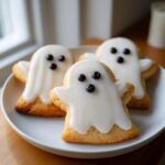 Three adorable Ghost Sugar Cookies (Halloween) decorated with white icing and dark chocolate chip eyes.