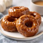 A stack of delicious Maple Glazed Pumpkin Spice Donuts on a white plate, ready to eat.