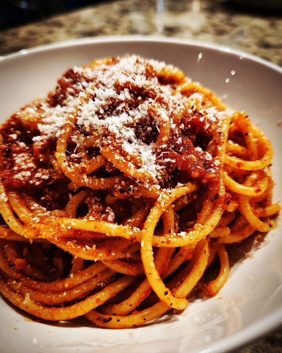 A bowl of delicious pasta recipe topped with tomato sauce and grated cheese.