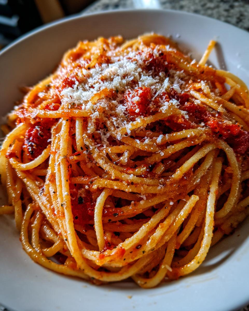 Bowl of spaghetti with tomato sauce and grated cheese, a simple and delicious pasta recipe.