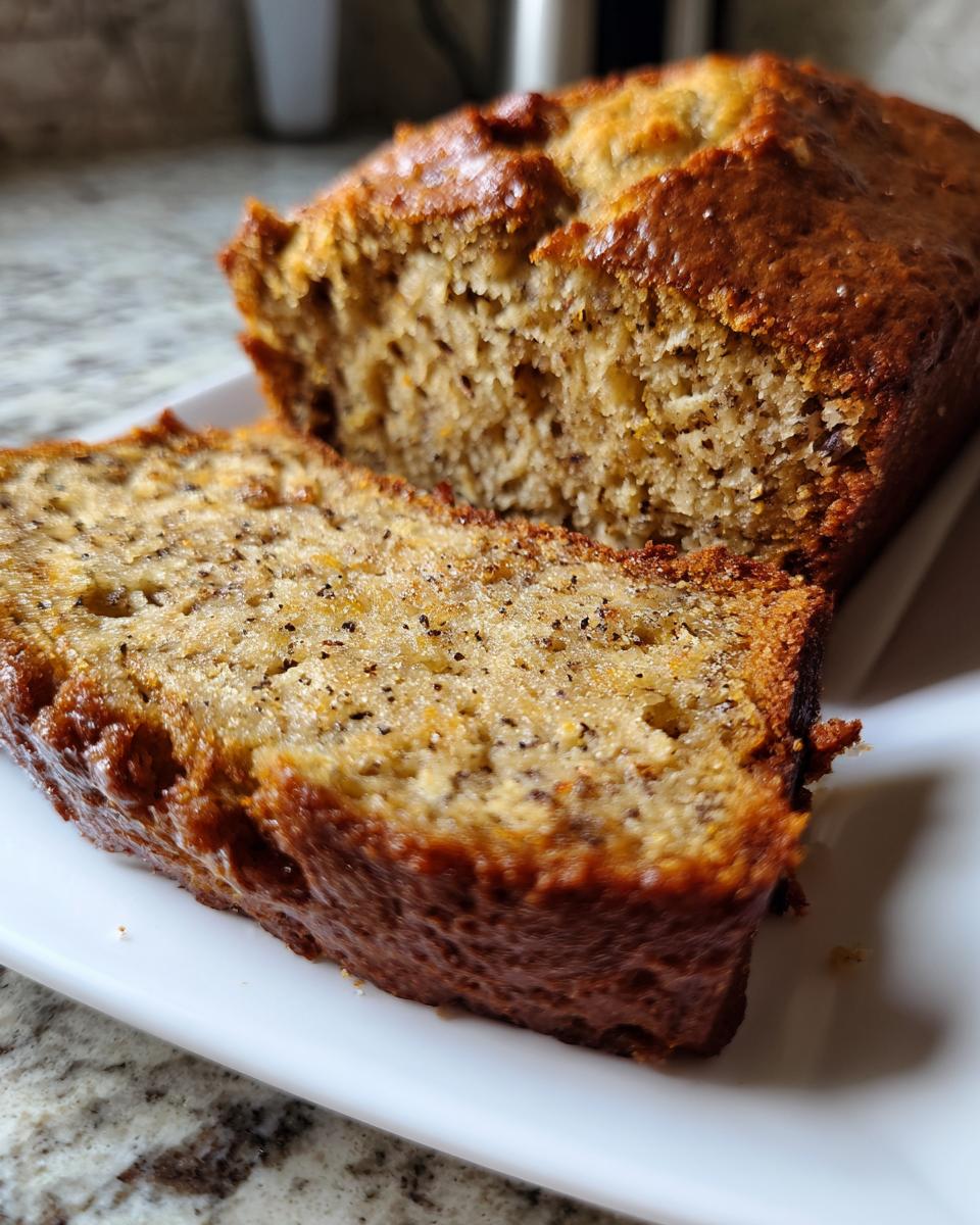 A close-up of a moist slice of pumpkin banana bread, showcasing its texture and dark specks.