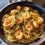 Close-up of shrimp pasta recipes in a pan, featuring spaghetti, succulent shrimp, garlic, and fresh parsley.