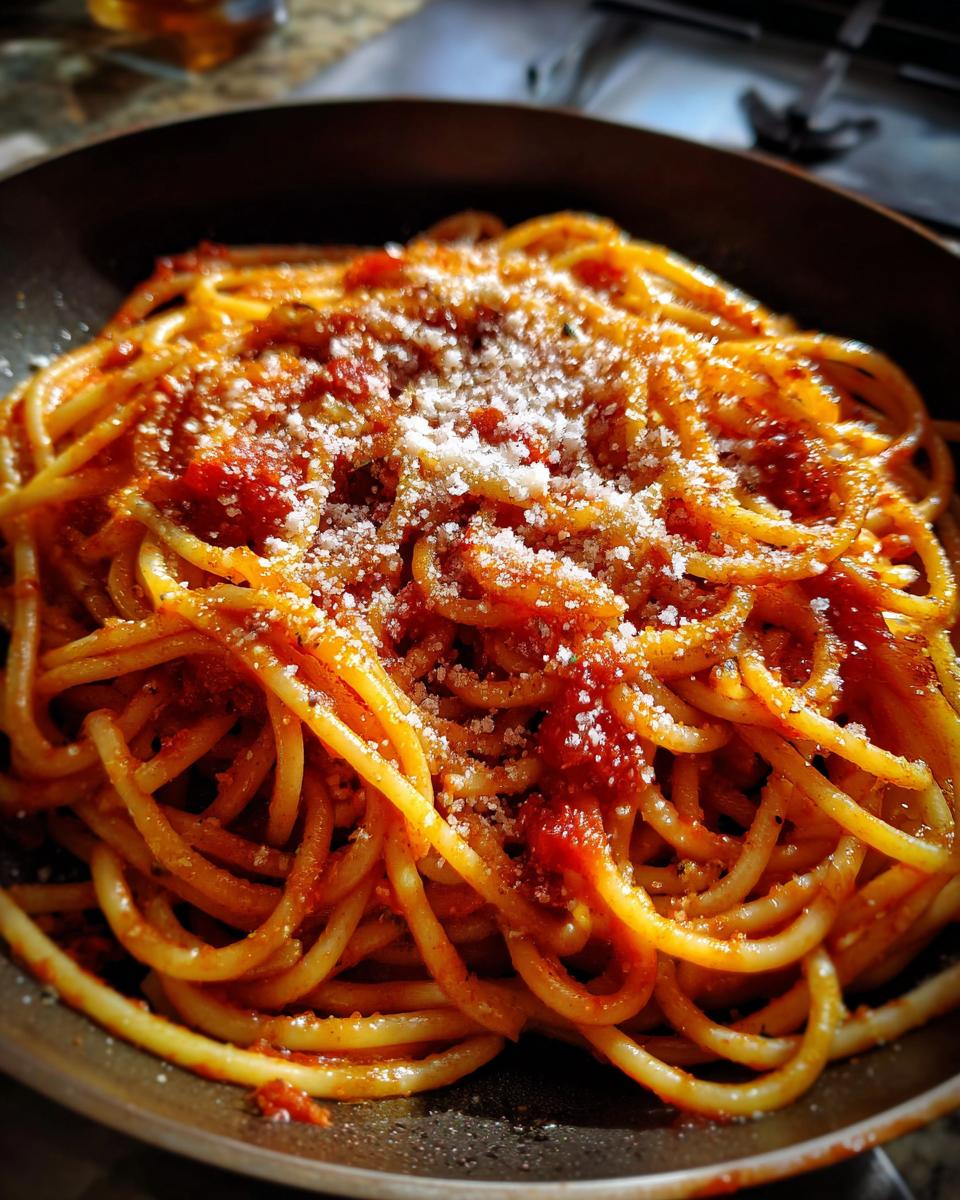Close-up of a pasta recipe featuring spaghetti with tomato sauce and grated cheese topping.