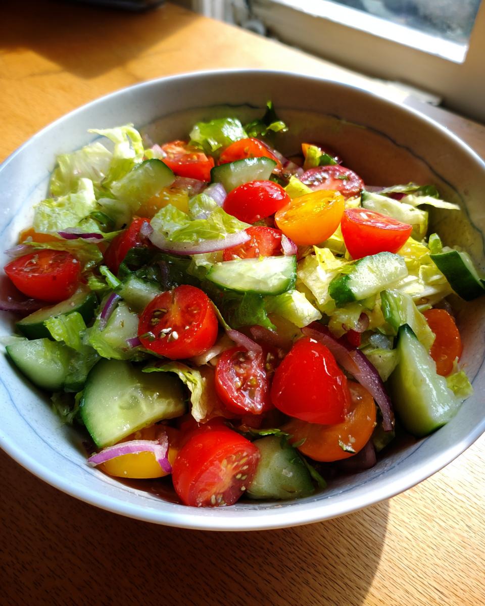 Bowl of summer salad recipes featuring fresh lettuce, cucumbers, red onions, and juicy red and yellow cherry tomatoes.