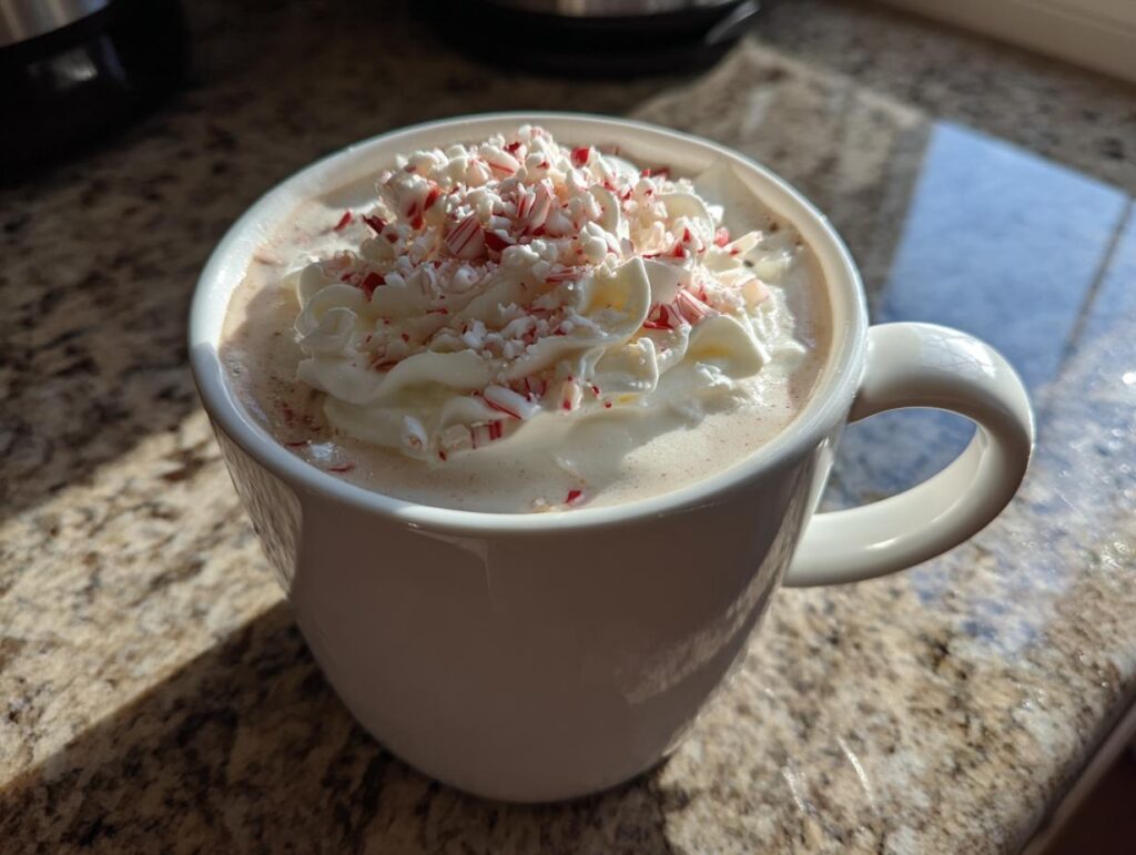 A festive White Chocolate Peppermint Mocha coffee topped with whipped cream and crushed candy canes.