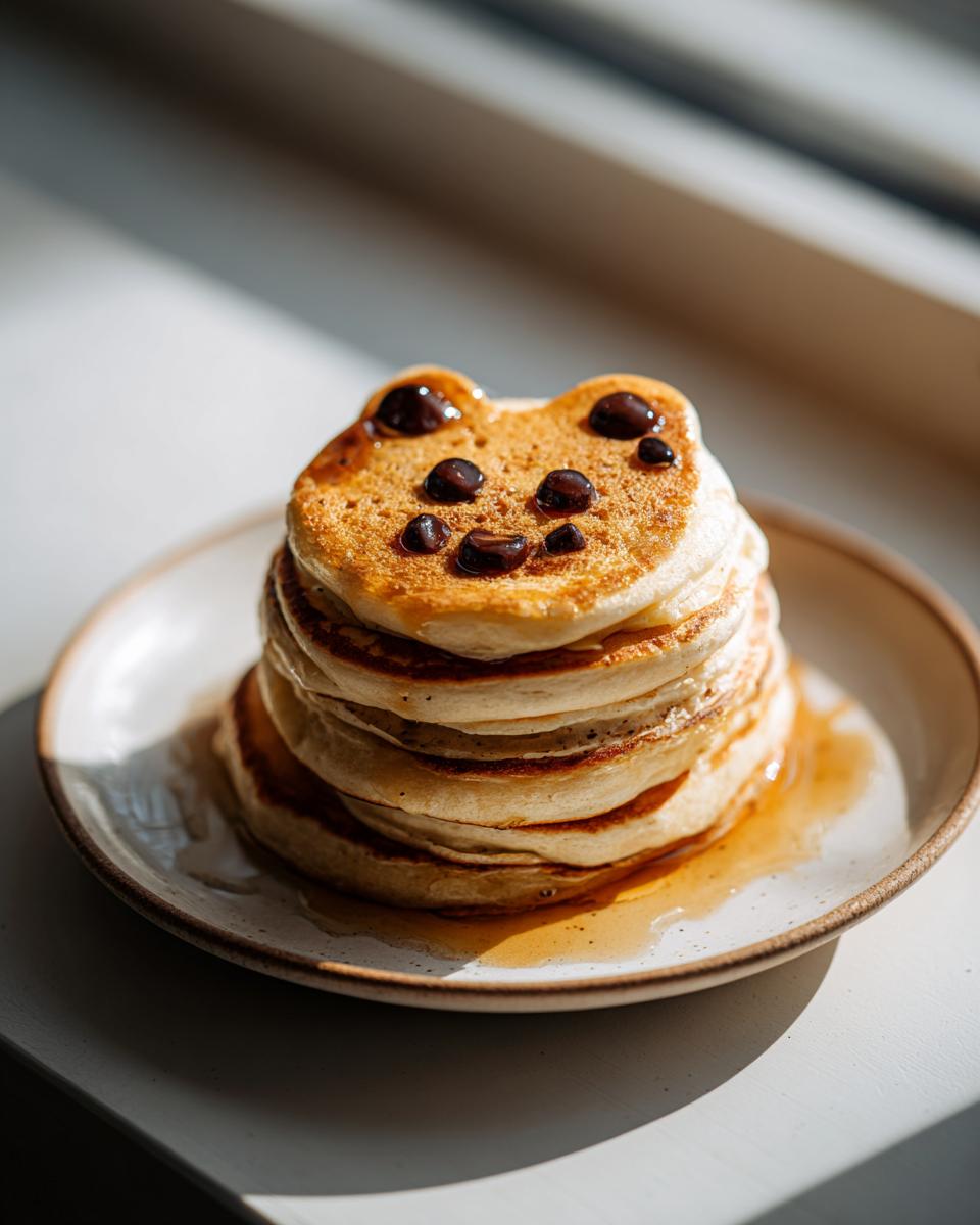 Stack of pancakes shaped like a cat's face, decorated with blueberries for eyes and mouth, part of fun Halloween breakfast ideas.
