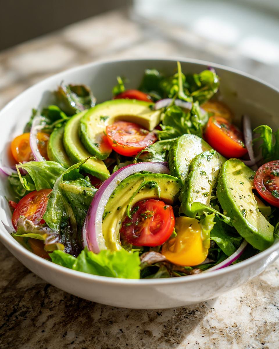 A vibrant bowl of avocado, cherry tomatoes, and red onion salad, a perfect healthy lunch idea.