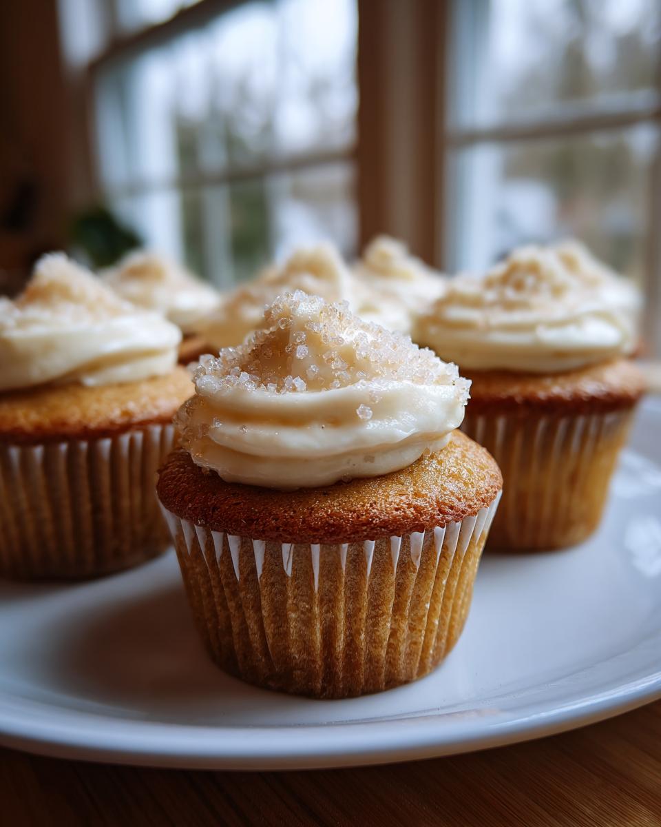 Close-up of cupcakes topped with creamy frosting and sugar sprinkles on a white plate.