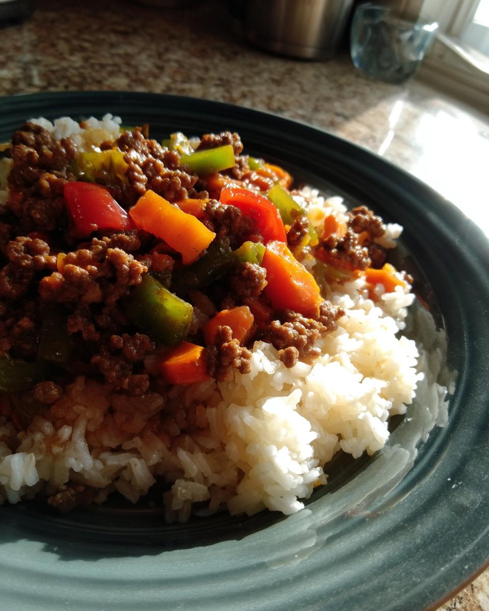 A close-up of a plate with fluffy white rice topped with seasoned ground beef and colorful chopped bell peppers and carrots, perfect for easy dinner recipes.