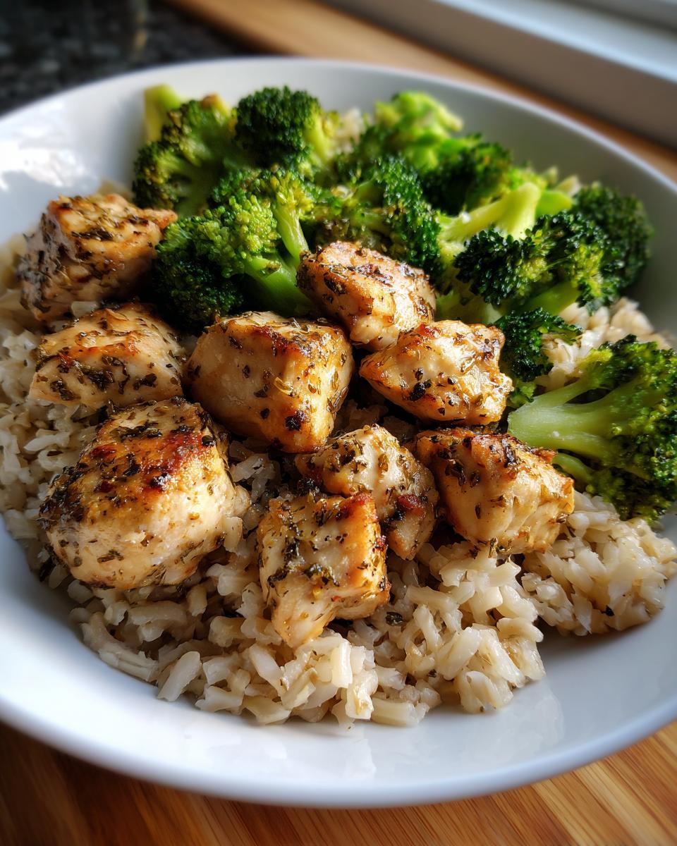 Grilled chicken pieces served with steamed broccoli and brown rice in a white bowl, an easy healthy dinner recipes option.