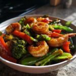 A bowl of shrimp and veggie stir fry with broccoli, red bell pepper, and snap peas.