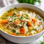 Bowl of instant pot chicken and brown rice soup with carrots and parsley garnish