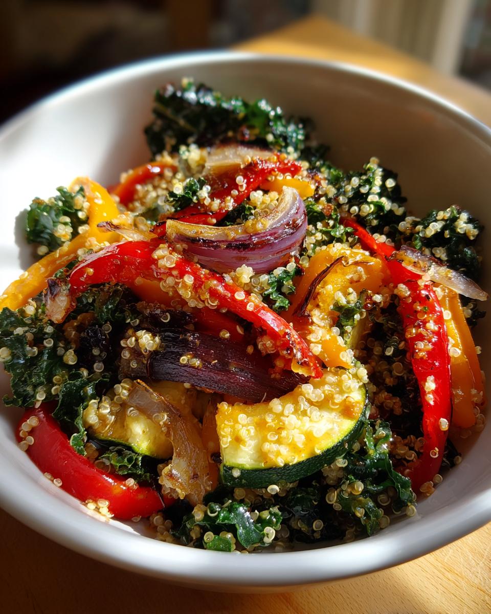 Bowl of kale quinoa salad with roasted red and yellow peppers, onions, and zucchini.