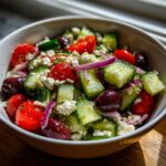 Bowl of mediterranean salad with cucumber, olives, cherry tomatoes, red onion, and feta cheese