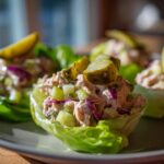 Tuna salad lettuce cups with pickles on a plate, featuring diced cucumbers and red onions