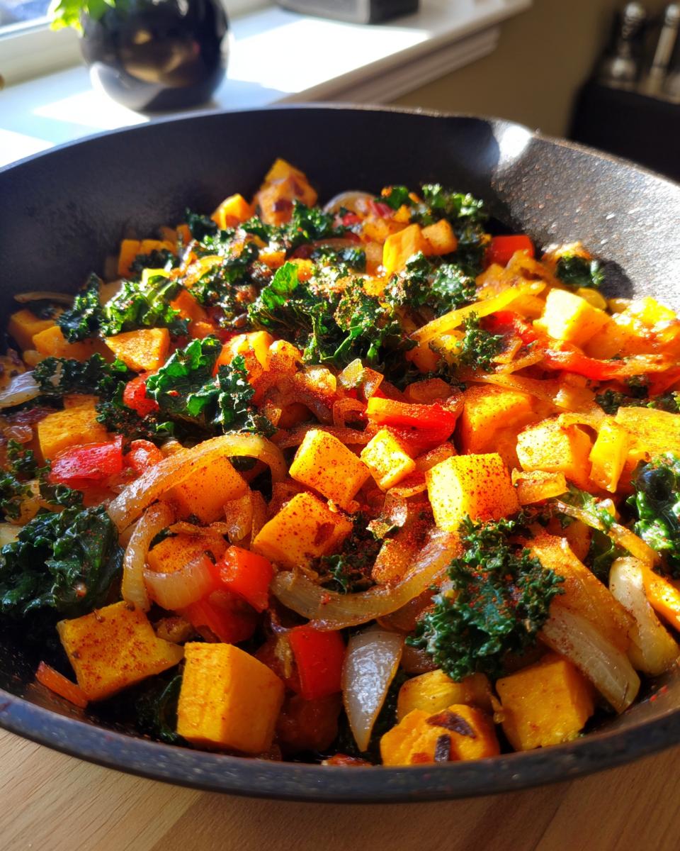 Skillet filled with veggie packed hash with sweet potatoes, kale, onions, and red peppers.