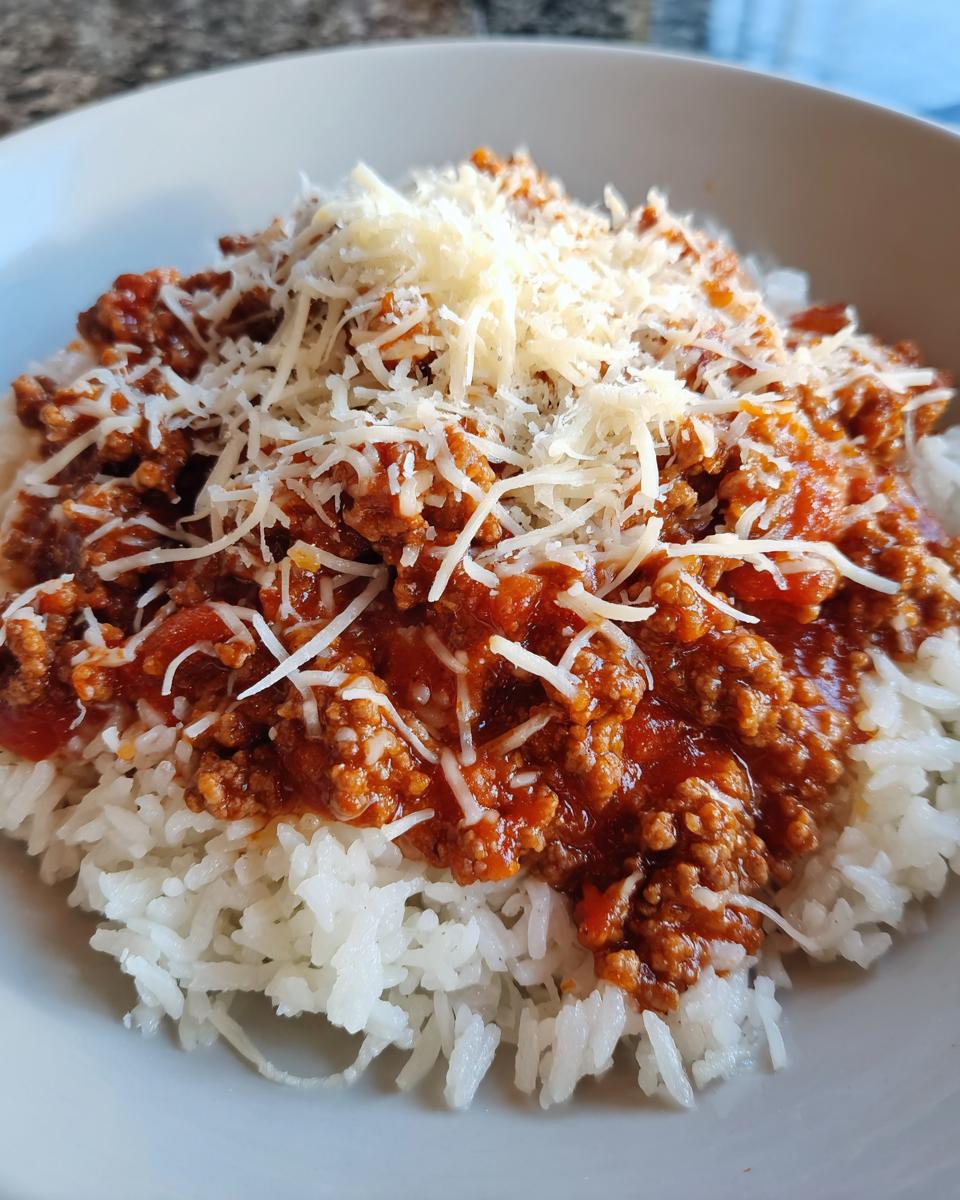 Plate of white rice topped with beef tomato sauce and shredded cheese, a family friendly dinner recipes dish