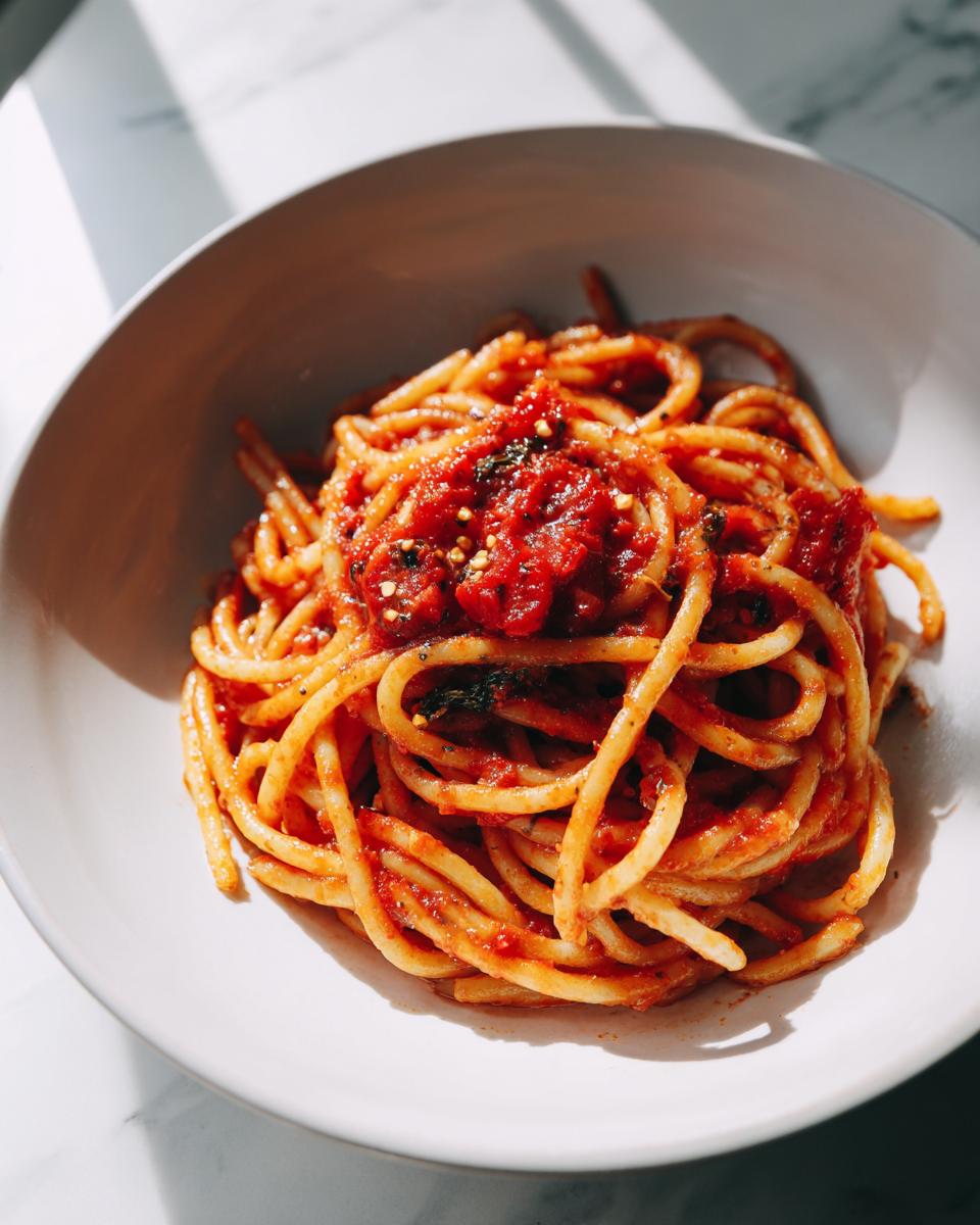 Plate of spaghetti pasta topped with red tomato sauce and herbs, budget friendly meals