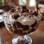 Glass bowl filled with chocolate trifle recipe layers of cake, cream, and chocolate shavings