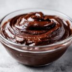 Close-up of creamy chocolate pudding dessert swirled in a clear glass bowl.