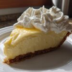 Slice of creamy lemon pie with graham cracker crust and whipped cream on top
