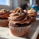 Close-up of Easter chocolate cupcakes with chocolate frosting and colorful sprinkles.