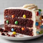 Close-up of a slice of Easter chocolate pinata cake decorated with colorful candy-coated chocolates.