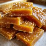 Close-up of golden brown salted caramel candy squares sprinkled with coarse salt.