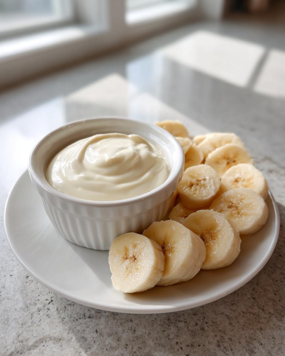 Sliced banana pieces served with creamy yogurt dip on a white plate, kid friendly snack recipes.