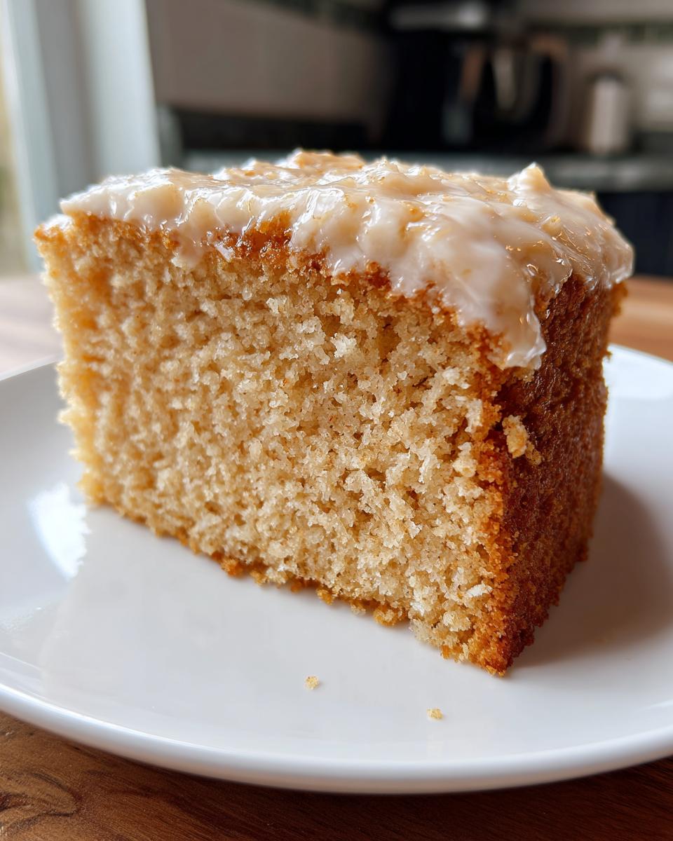 Close-up of a moist cake slice topped with creamy icing on a white plate for simple baking recipes