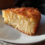 Close-up of a moist coconut cake slice on a white plate for April holiday dessert recipes