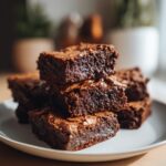 Close-up of a stack of moist, fudgy brownies on a white plate for easy brownie recipes