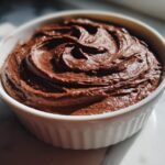Close-up of rich chocolate frosting swirled in a white bowl, perfect for chocolate frosting recipes.
