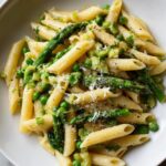 Pasta with asparagus, peas, and grated cheese in a white bowl, a spring dinner recipes dish