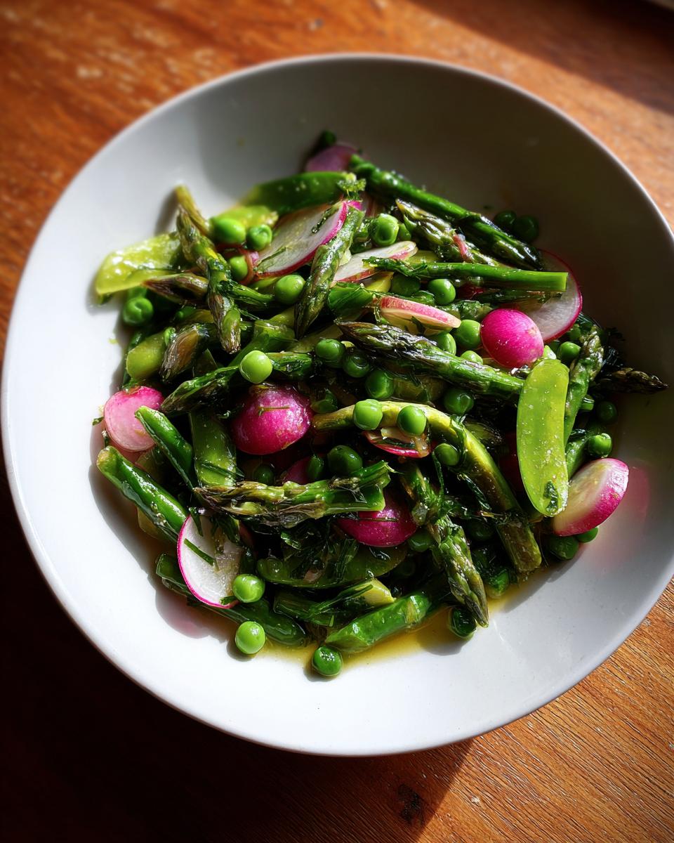 Bowl of vibrant spring vegetable side dishes with asparagus, peas, radishes, and snap peas.
