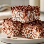 Close-up of stacked chocolate rice krispie treats with melted chocolate chips on top.