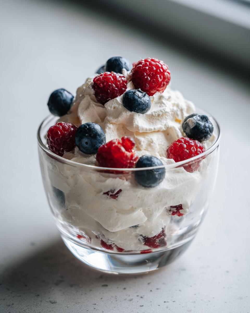 Glass cup filled with whipped cream topped with fresh raspberries and blueberries spring party dessert recipes